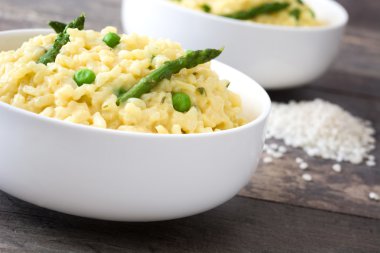 Risotto ile kuşkonmaz, maydanoz ve rustik ahşap bir masa üzerinde bir kase bezelye