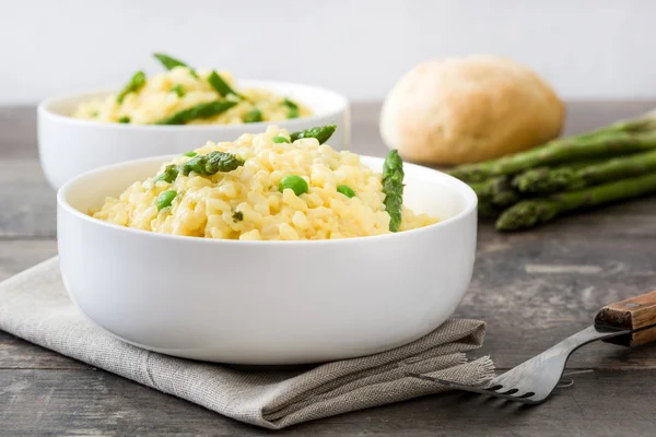 Risotto with asparagus, parsley and peas in a bowl on a rustic wooden table — Stock Photo, Image