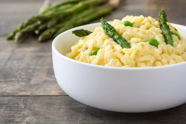 Risotto with asparagus, parsley and peas in a bowl on a rustic wooden table — Stock Photo, Image