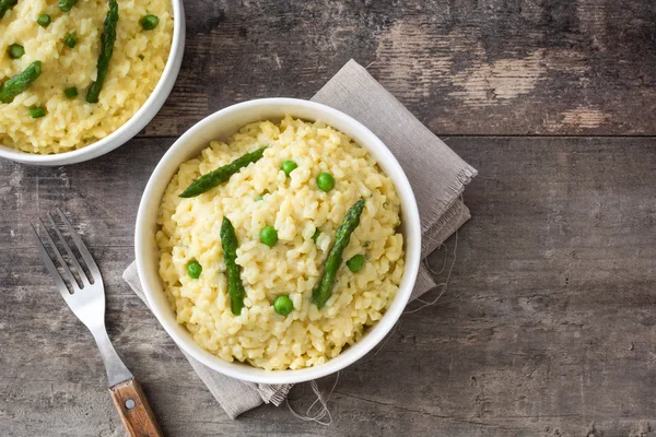 Risotto with asparagus, parsley and peas on rustic wooden background — Stock Photo, Image