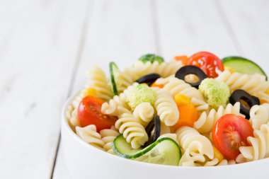 Beyaz ahşap masa üzerinde bir kapta makarna salatası