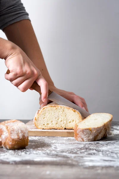 Mujer cortando pan en una mesa de madera rústica — Foto de Stock