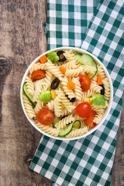 Rustik ahşap bir masa üzerinde bir kapta makarna salatası