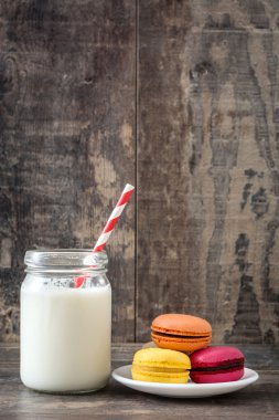 Süt ve rustik ahşap arka plan üzerinde renkli macaroons