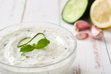 Cacık ve malzemelerin üzerine beyaz bir ahşap masa