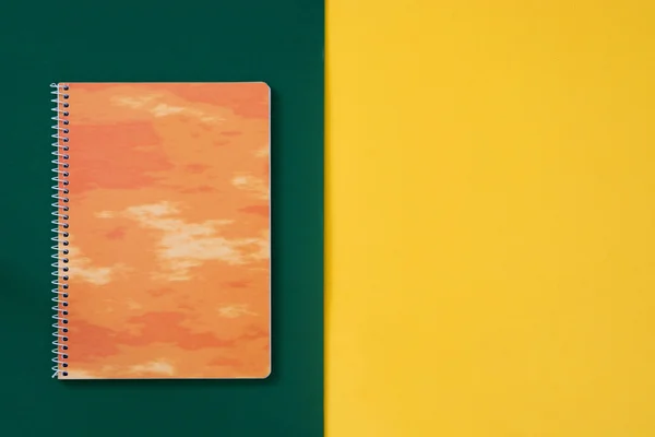 Oranges Notizbuch auf grünem und gelbem Hintergrund — Stockfoto
