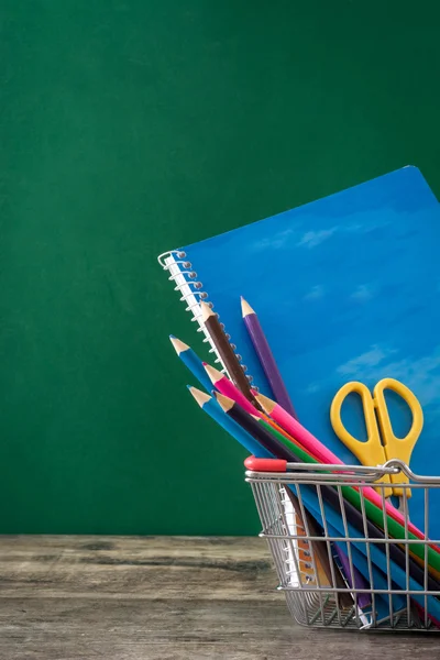 Fournitures scolaires sur une table en bois et fond de tableau noir — Photo