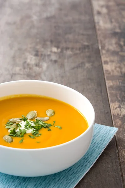 Kürbissuppe und Kürbiskerne auf rustikalem Holzgrund — Stockfoto