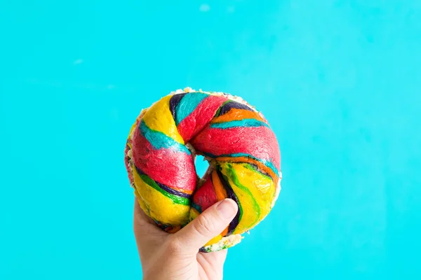 Bagel coloré au fromage et saupoudrer à la main sur fond bleu — Photo