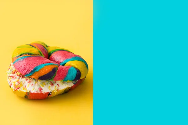 Colorful bagel on yellow and blue background