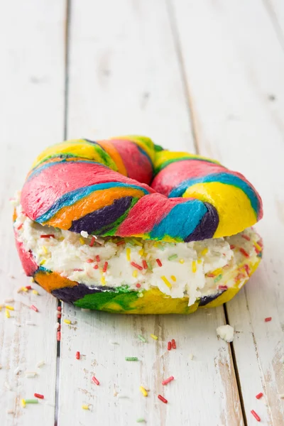 Bagel colorato con formaggio e spolverate su legno bianco — Foto Stock