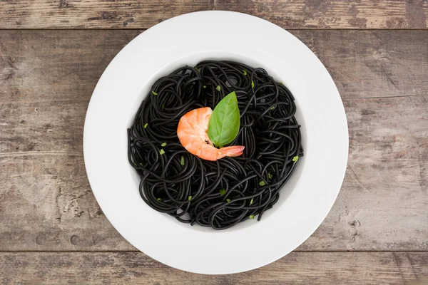 Zwarte spaghetti met garnalen op rustieke houten tafel — Stockfoto