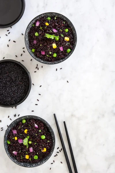 Arroz negro en un tazón y verduras en una mesa de mármol —  Fotos de Stock