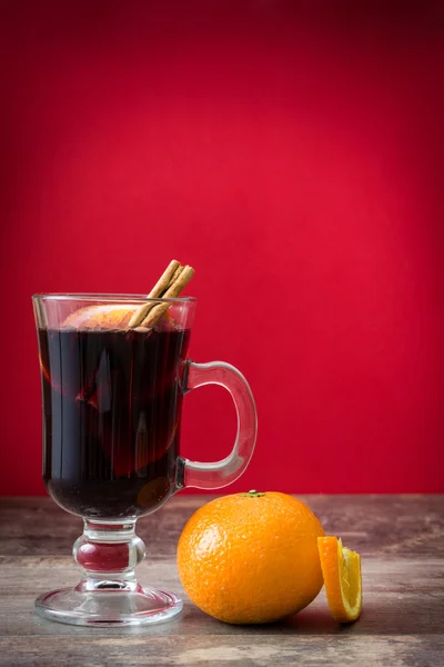 Vin chaud de Noël sur table en bois et fond rouge — Photo