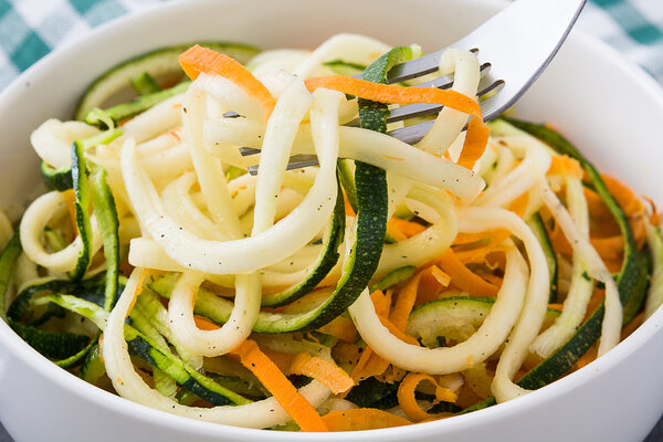 Carrot and zucchini noodles on a rustic wooden table