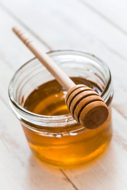 Beyaz ahşap masa üzerinde bir kavanoz bal bal ayı