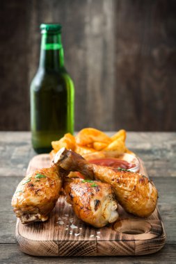 Kızartma tavuk sopaları ile cips ve bira ahşap arka plan üzerinde