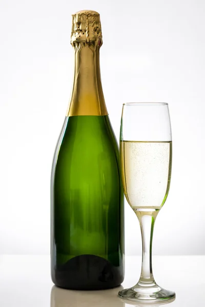 Champagne bottle with a glass cup on white background — Stock Photo, Image
