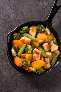 Tavuğu sebzeyle karıştır, siyah arka planda demir tavada.