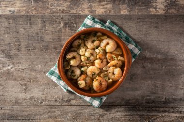 Tahta masadaki çömlek içinde sarımsaklı karides. Üst görünüm