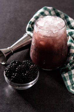 Siyah arka planda soğuk bardakta taze böğürtlen kokteyli.