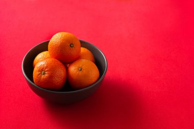 Kırmızı arka planda taze mandalinalar. Anlaşıldı.