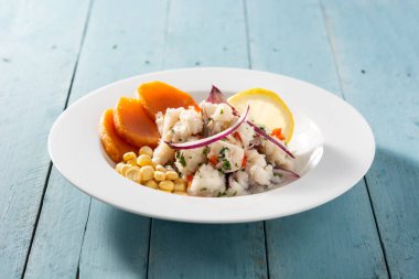 Balık, tatlı patates, mısır ve sebzeli geleneksel Peru ceviche 'si mavi ahşap masada.