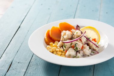 Balık, tatlı patates, mısır ve sebzeli geleneksel Peru ceviche 'si mavi ahşap masada.