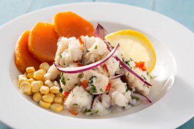 Balık, tatlı patates, mısır ve sebzeli geleneksel Peru ceviche 'si mavi ahşap masada.