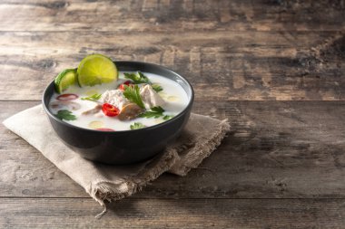 Geleneksel Tayland yemeği Tom Kha Gai ahşap masada kasede. Boşluğu kopyala.