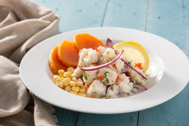 Balık, tatlı patates, mısır ve sebzeli geleneksel Peru ceviche 'si mavi ahşap masada.