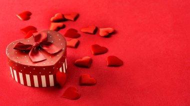 Kalp şeklinde bir hediye kutusu ve kırmızı arka planda kalpler. Boşluğu kopyala