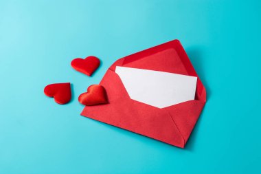 Mavi arka planda kırmızı bir zarftan kalpler çıkıyor.