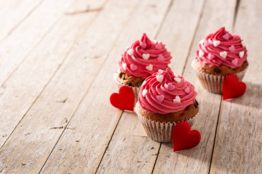 Şeker kalplerle süslenmiş kek ve ahşap masada Sevgililer Günü için aşk oku.