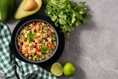 Mexican salad with quinoa in bowl on gray stone background. Top view. Copy space