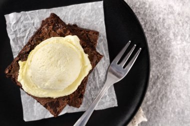 Gri taşlı arka planda vanilyalı dondurmalı brownie.