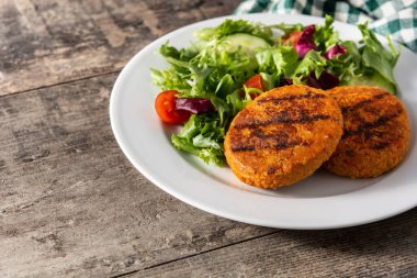 Tahta masada lezzetli, sağlıklı nohut burger ve salata. Boşluğu kopyala