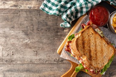 Pastırmalı BLT sandviç, ahşap masada marul ve domates