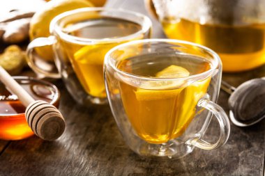 Limonlu zencefil çayı ve ahşap masada kristal bardakta bal.