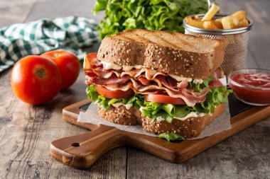 Pastırmalı BLT sandviç, ahşap masada marul ve domates