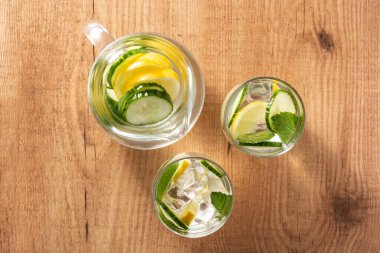 Ahşap masada salatalık ve limon ile sulu su. Üst görünüm