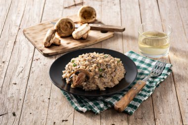 Ahşap masada siyah tabakta mantarlı risotto.