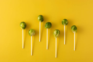 Sarı zemin üzerinde lolipop çubukları olan brussel lahanaları.