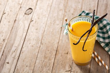 Tahta masadaki cam bardakta vanilyalı milkshake. Boşluğu kopyala