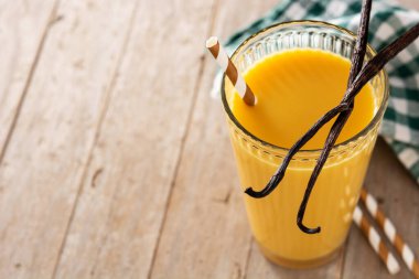 Tahta masadaki cam bardakta vanilyalı milkshake. Boşluğu kopyala