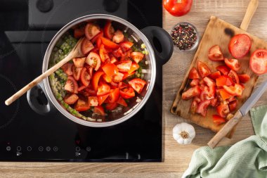 Mutfaktaki tencerede domates sosu pişirmek. Üst görünüm