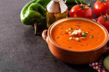 Güveç tenceresinde gazpacho çorbası ve siyah arka planda malzemeler. Tipik İspanyol yemekleri.