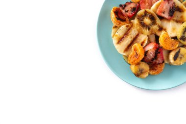 Beyaz arka planda izole edilmiş mavi bir tabakta ızgara meyve. Boşluğu kopyala