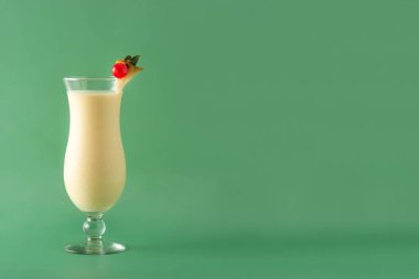 Yeşil arka planda cam kaplı Pina Colada kokteyli. Boşluğu kopyala
