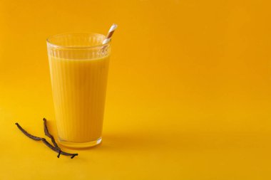 Sarı arka planda cam kaplı vanilyalı milkshake.
